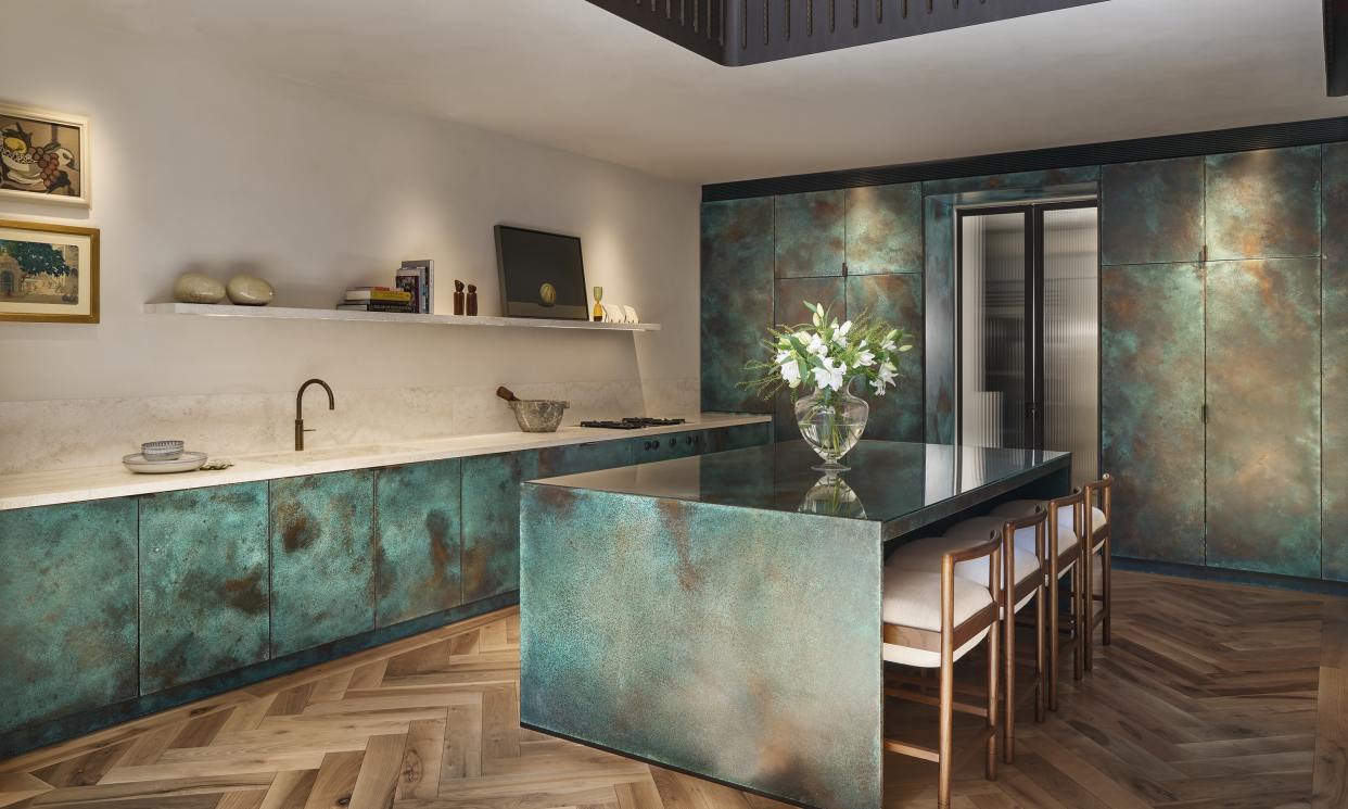 Verdigris panelled copper kitchen featuring travertine marble