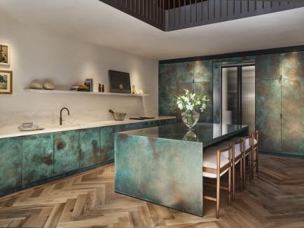 Verdigris panelled copper kitchen featuring travertine marble